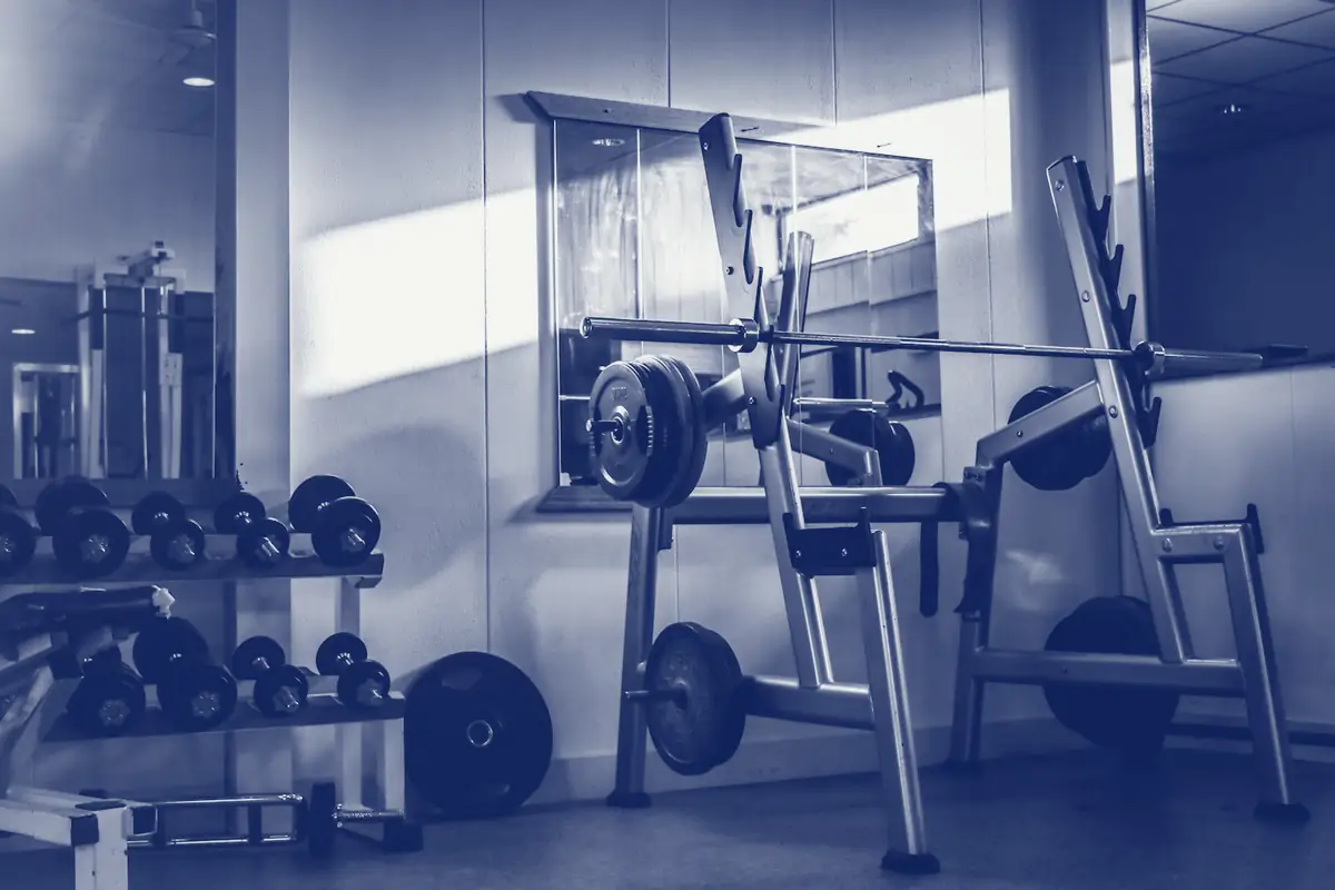 A barbell rack and dumbbells on a gym floor